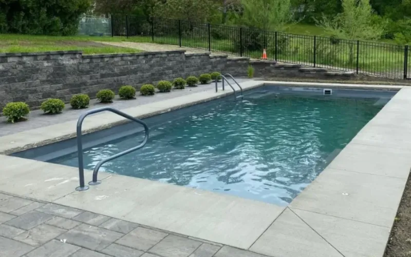 concrete pool deck with brick paver patio and elaborate retaining wall